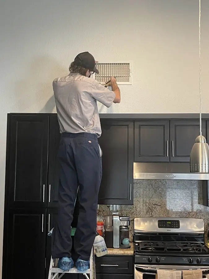 Technician inspecting an air vent during HVAC service in Carson